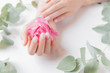 © Parilov - Stylish plain female hand manicure gel polish on white background with flower, top view. Concept natural organic skin care