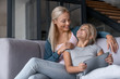 Happy family mom and kid daughter using digital tablet sitting on sofa