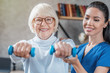 © InsideCreativeHouse - Old woman training with physiotherapist using dumbbells at home