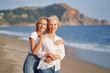 © luengo_ua - Outdoor portrait of smiling happy caucasian senior mother with her adult daughter hugging and looking at the camera on sea beach.
