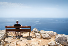 Guy Sitting On Wooden Bench And Looking At The Blue Ocean In Ayia Napa, Cape Greco National Forest Park, Cyprus