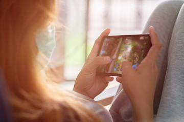 Asian girl are playing the mobile game with blurred on screen at home. The hand is touch screen for play game in the smartphone.