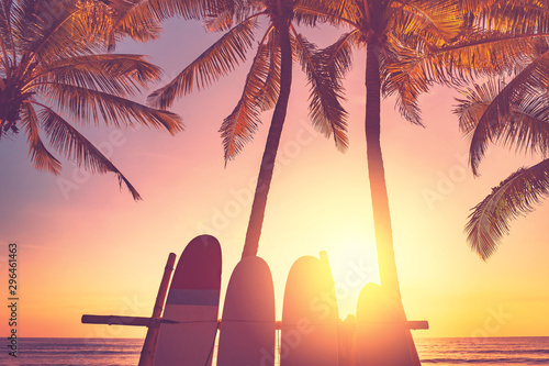 Surfboard and palm tree on beach background.