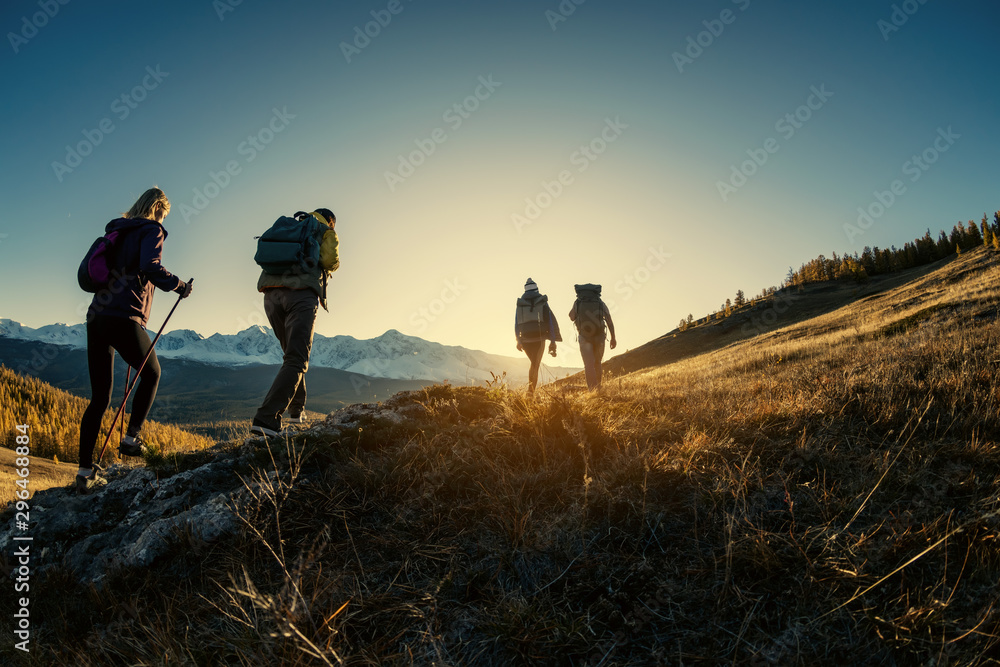 Group of hikers walks in mountains at sunset - obrazy, fototapety, plakaty 