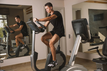 An athlete is engaged in the gym, a Young man does cardio on an exercise bike