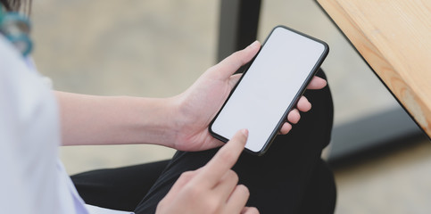 Wall Mural - Close-up view of young female doctor touching blank screen smartphone