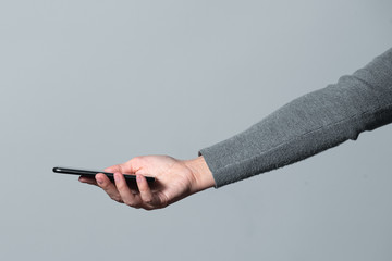 Mobile phone in female hand isolated on gray background.