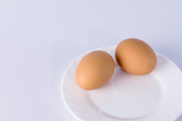 Two boiled eggs on a white plate.