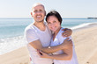 © caftor - man and a middle-aged woman in white T-shirt cuddling on the beach