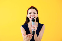 Beautiful Young Female Singer With Microphone On Color Background