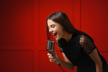 Wall Mural - Beautiful young female singer with microphone on color background