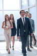 © ASDF - businessman walking in front of his business team