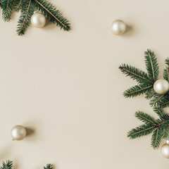 Wall Mural - Christmas / New Year holiday composition. Mock up frame with blank copy space, fir needle branches, Christmas baubles on beige background. Flat lay, top view festive concept.