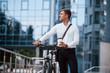 © standret - Ready for the work. Businessman in formal clothes with black bicycle is in the city