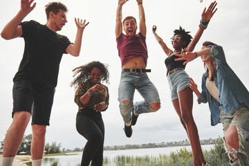 Wall Mural - Celebrate while jumping. Group of people have picnic on the beach. Friends have fun at weekend time