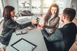 © HBS - Side view shot of cheerful wife and husband making key handover from estate saler. Group of people in business clothes siting at the table in office, finishing a big deal. Property purchase concept