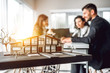 © HBS - Close up image of house model with group business people on blurred background in building design studio. Architecture project concept