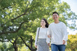 © west_photo - 綺麗な緑を背景に仲良く歩く若い男女