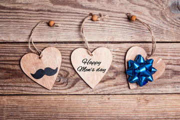 World men's day card with hearts, mustache and bow on old wooden table.