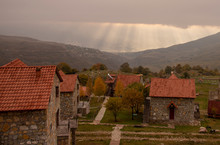The Sun's Rays Through The Clouds Illuminate The Tiled Roofs Of Houses.