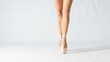 Close-up of dancing legs of ballerina wearing white pointe on a white background.