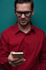 Wall Mural - Portrait of a positive young man in glasses with phone