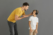 © Pixel-Shot - Little boy with headphones ignoring his angry father against grey background