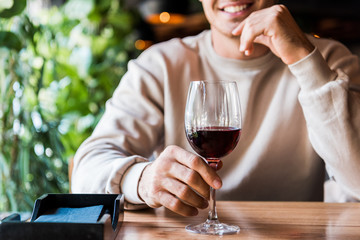 Canvas Print - cropped view of cheerful man sitting in restaurant with glass of wine