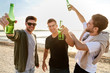 friendship and leisure concept - group of happy young men or male friends toasting non alcoholic beer on summer beach
