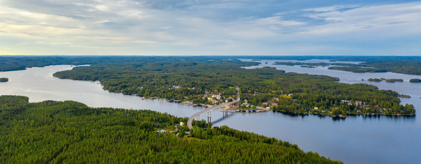 Sticker - Aerial view on the bridge over the lake and trees in the forest on the shore. Blue lakes, islands and green forests from above on a cloudy summer day. Lake landscape in Finland, Puumala.