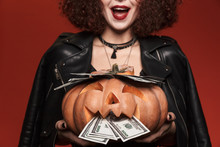 Image Of Witch Girl In Halloween Costume Holding Pumpkin With Money