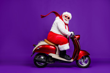 Wall Mural - Photo of fat santa claus role man rushing newyear x-mas theme party by bike cool modern style wear sun spectacles trousers hat suspenders isolated purple background