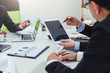© amnaj - Broker holding pen pointing to graph data to show investors see growth in business investment.