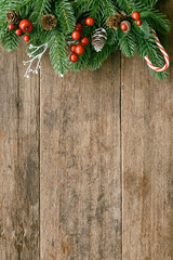 wood table plank in vertical with pine leaves and pine cones, holly balls and candy cane in christma