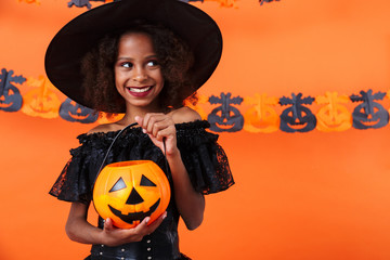 Image of joyful african american girl smiling and holding toy pumpkin