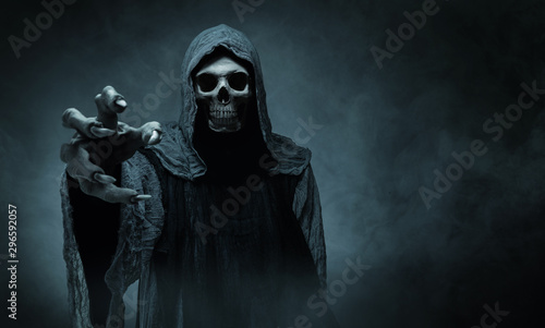 Fotografía Grim reaper reaching towards the camera over dark background with copy space