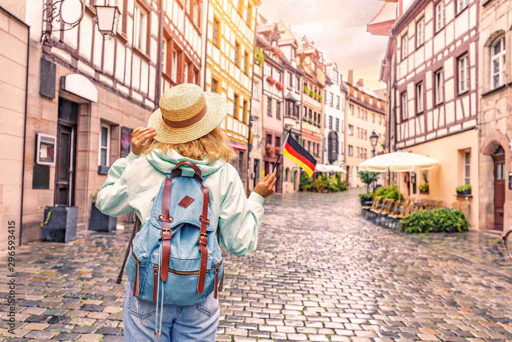 Young asian woman tourist traveling with german flag near the famous half-timbered street in Nuremberg old town - obrazy, fototapety, plakaty 