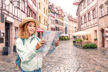 Wall Mural - Happy Asian girl tourist and traveller reading map on the famous street of Nuremberg old town. Sights Of Germany.