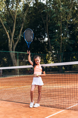 Attractive little girl in sportwear is playing tennis