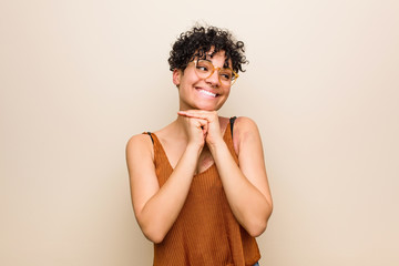 Wall Mural - Young african american woman with skin birth mark keeps hands under chin, is looking happily aside.