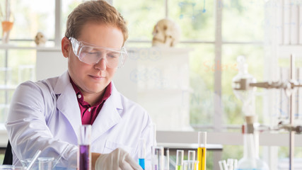 Young Caucasian scientists making testing with test tube while doing research at science laboratory.