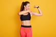 © sementsova321 - Horizontal shot of beautiful brunette young woman dresses black top and leggins, pointing at her bicep. Three quarter length studio shot isolated over yellow background. Healthy lifestyle concept.