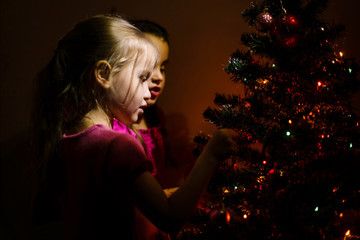 Wall Mural - little girls stand near a small Christmas tree in a dark room