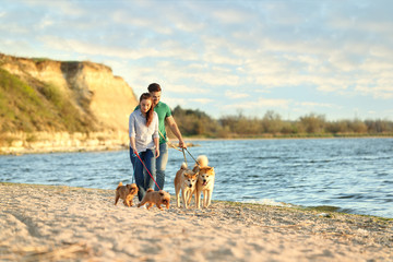 Young couple walking their adorable dogs near river