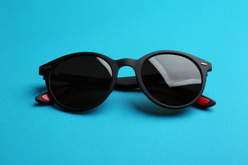 Stylish sunglasses on blue background. Fashionable accessory