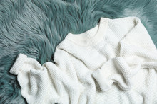 White Knitted Sweater On Green Fur Rug, Flat Lay