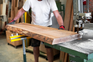 Canvas Print - Carpenter sawing a wooden plank on a band saw