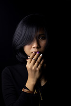 Asian Short Haired Girl Wearing A Black Long-sleeved Shirt And Jewelry Made Of Metal And Leather, Sad Faces On A Black Background And Shadows
