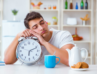 Canvas Print - Man with alarm clock falling asleep at breakfast