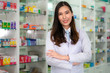 © ake1150 - Confident Asian young female pharmacist with a lovely friendly smile standing with folded arms in the pharmacy drugstore. Medicine, pharmaceutics, health care and people concept.